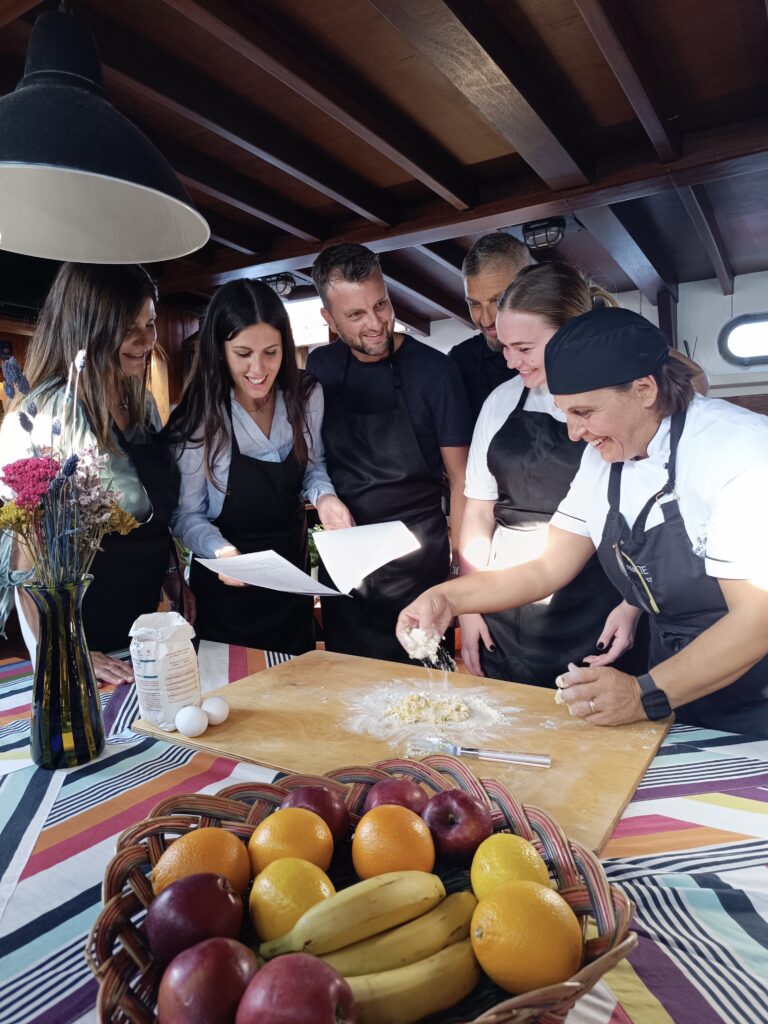 Cooking class in barca a Venezia con chef e gruppo che prepara pasta fresca