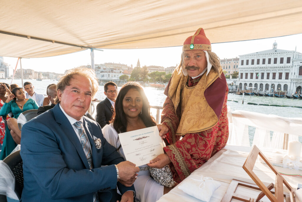 Cerimonia di matrimonio simbolico a Venezia su barca con celebrante in costume storico e sposi con certificato, vista su Piazza San Marco