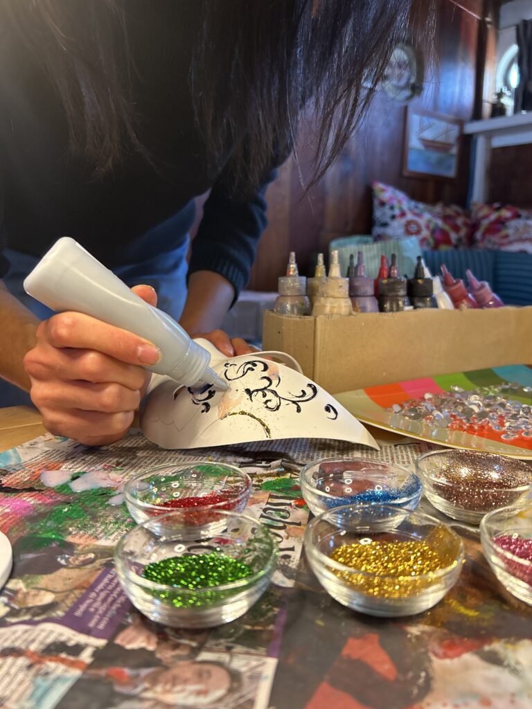 Decorazione di maschere veneziane in barca con colori e glitter durante attività di team building