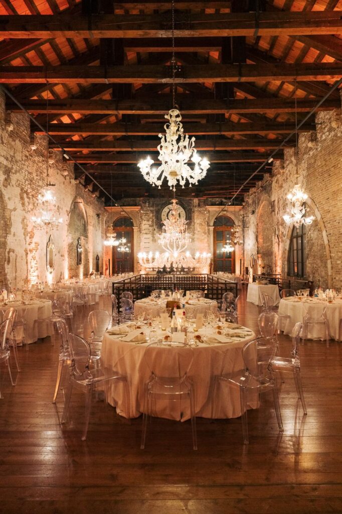 Cena di gala a Venezia in location storica con lampadari di vetro e allestimento elegante.