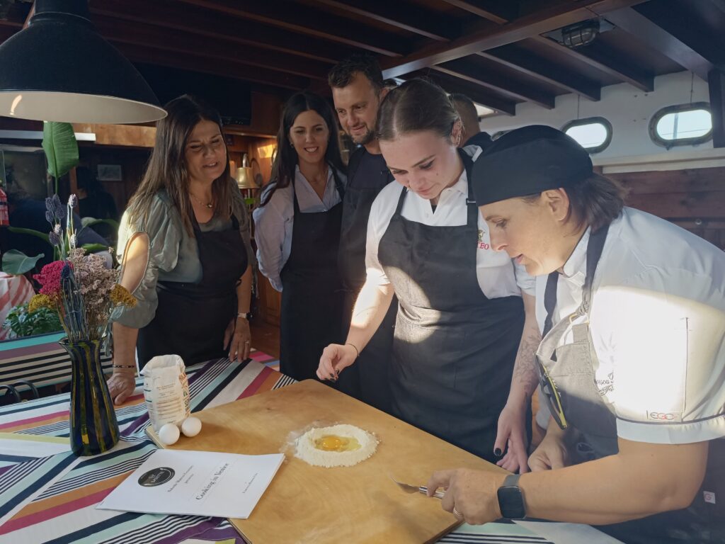 Corso di cucina a Venezia con team building: partecipanti preparano pasta fresca guidati da uno chef.